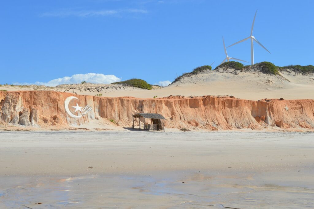 Red cliffs and wind turbines above the sea at Canoa Quebrada, by Nestor Roco