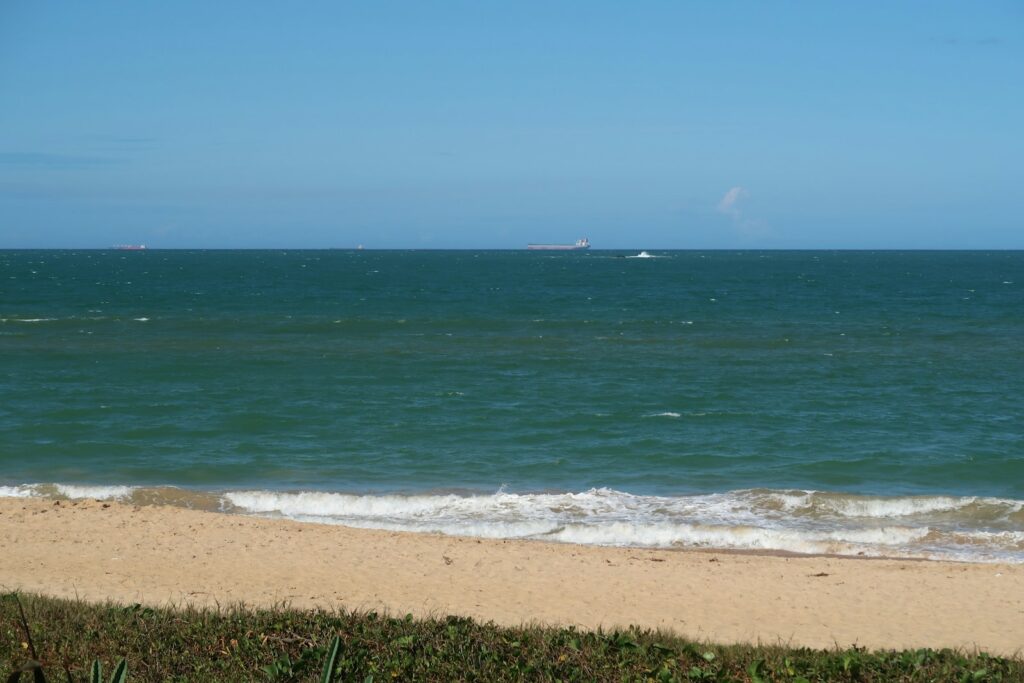A beach in Vila Velha with a boat offshore, by Nivaldo Martins