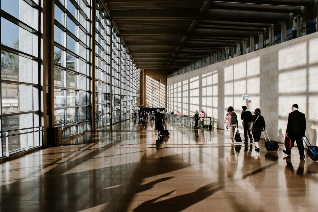International travelers walking through a sunlit airport terminal
