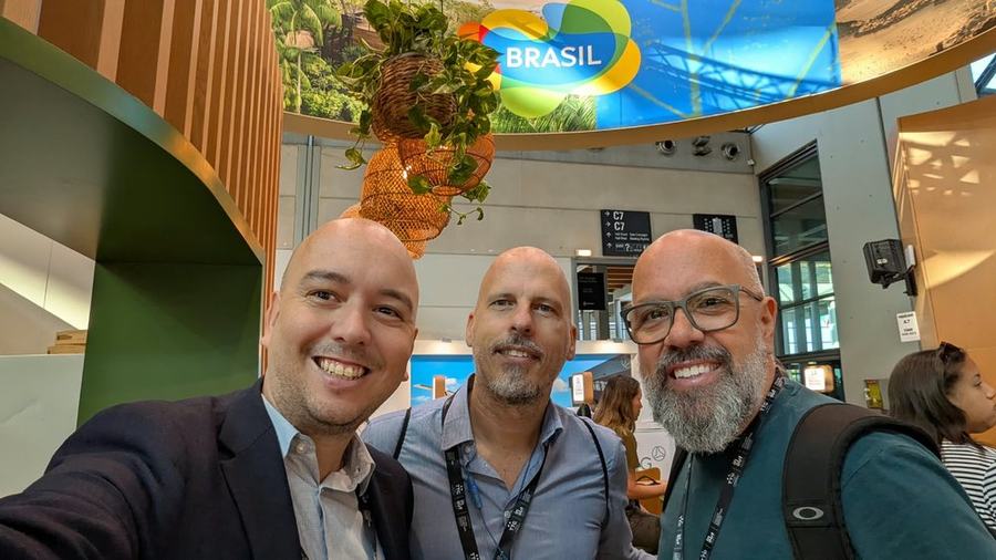 Three travel trade professionals under the Brasil sign at the national pavilion in Rimini